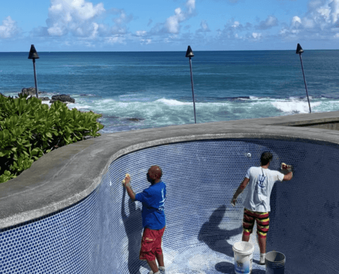 Employees of Neptune pool and spa in Honolulu maintaining and cleaning a swimming pool.