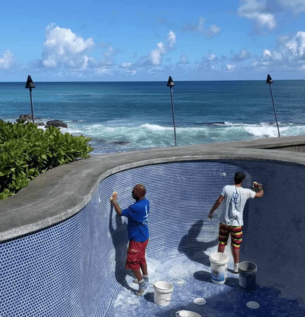 Employees of Neptune pool and spa in Honolulu maintaining and cleaning a swimming pool.
