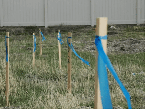 Wooden stakes mark out pool excavation for heavy equipment.